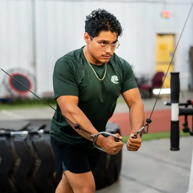 Corporate Event Photography & Videography in Pensacola | KDH Productions 10 Unconscious Faith fitness model in the gym doing cable flys wearing a green shirt and glasses