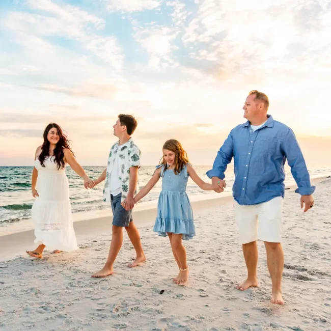 family portrait husband and wife with two kids holding hands on the beach