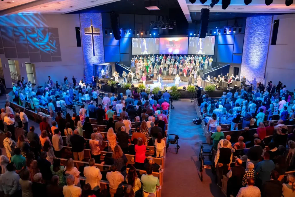 Corporate Event Photography & Videography 2 Packed venue under blue stage lighting, photographed from the balcony with the stage and choir in the distance