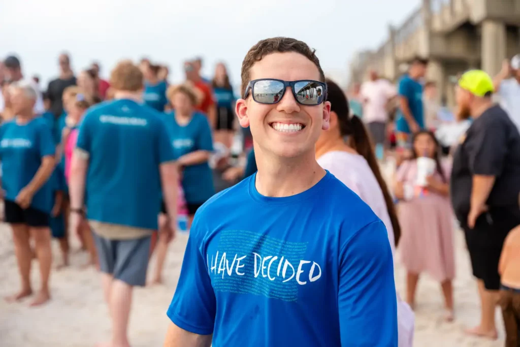 Corporate Event Photography & Videography 10 Candid portrait of an attendee in a branded event shirt, smiling, with the crowd behind him on the boardwalk
