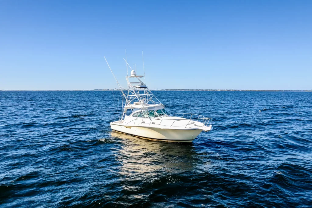 Marine Photography 2 Three-quarter exterior of a white sportfishing yacht at rest on flat blue water, outriggers and tuna tower against a clear sky