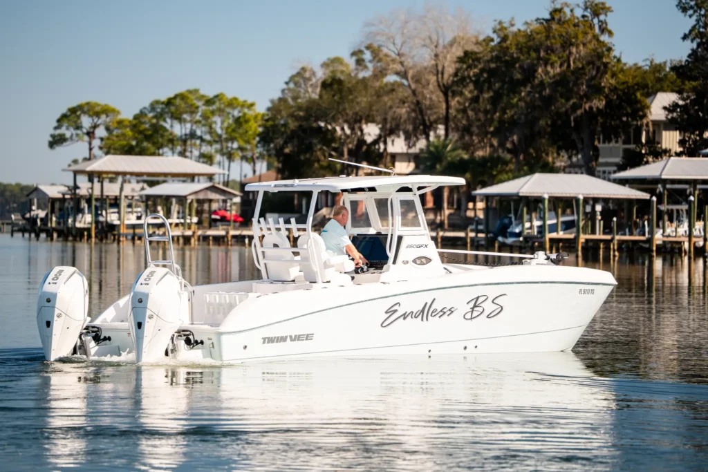 Twin Vee catamaran at rest on glassy water in front of waterfront homes