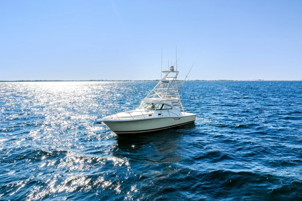 Side profile of a sportfishing yacht with the sun glittering off the water behind her