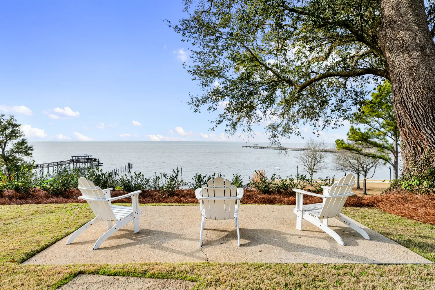White Adirondack chairs on a patio overlooking Mobile Bay at Emma's Bayhouse, Fairhope