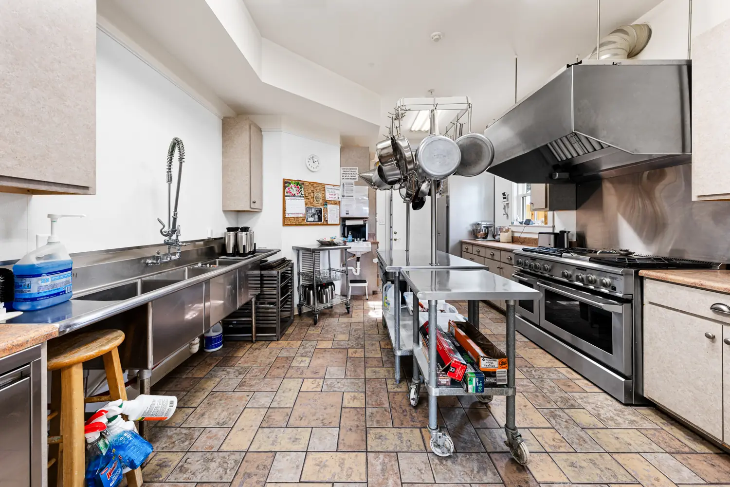 Commercial kitchen with a stainless range, hood and prep tables at Emma's Bayhouse in Fairhope