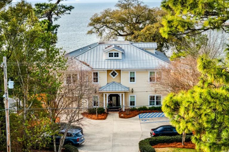 Aerial view of Emma's Bayhouse in Fairhope, Alabama, a bed and breakfast with a metal roof, with Mobile Bay behind it