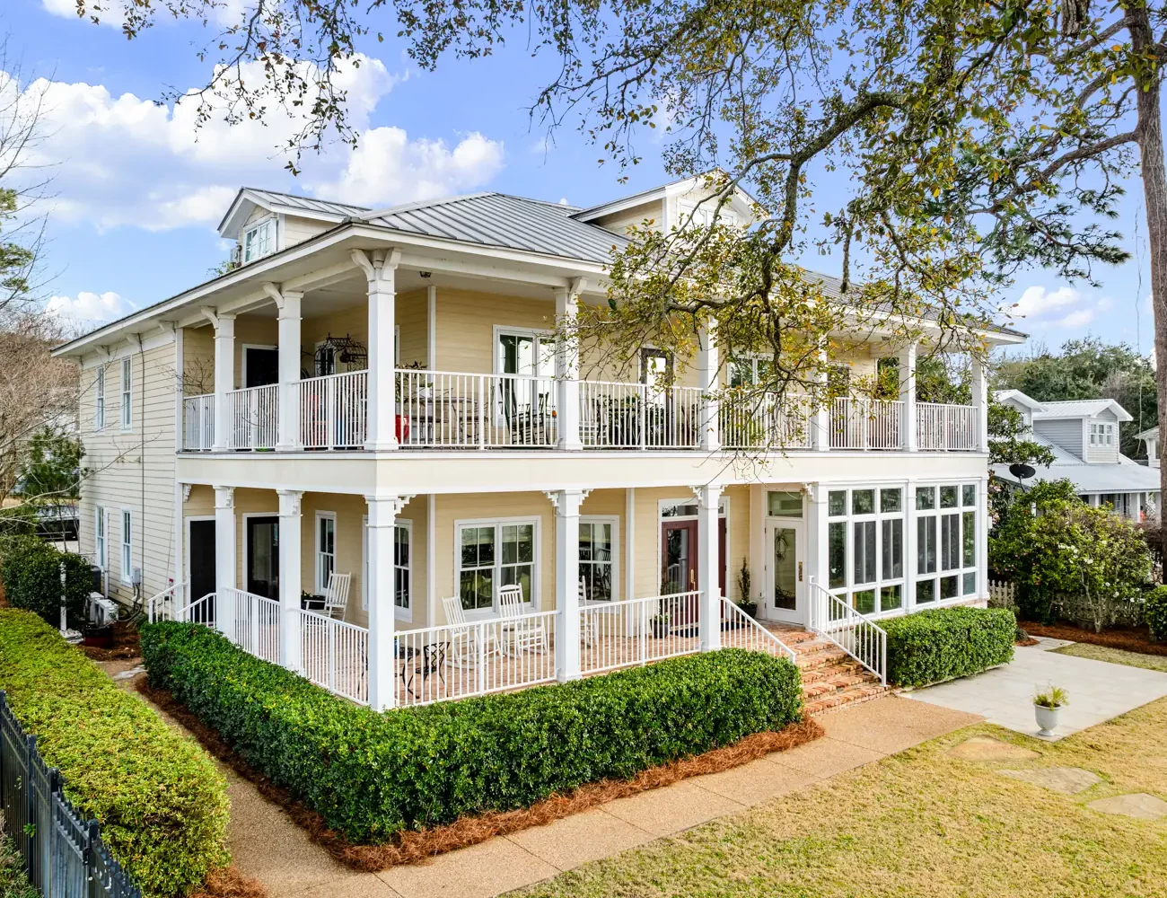 Bay side of Emma's Bayhouse in Fairhope, Alabama, with double wraparound porches and a lawn edged by hedges