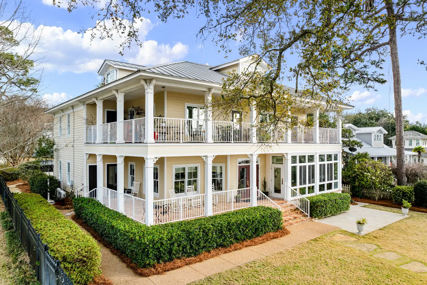 Bay side of Emma's Bayhouse in Fairhope, Alabama, with double wraparound porches and a lawn edged by hedges