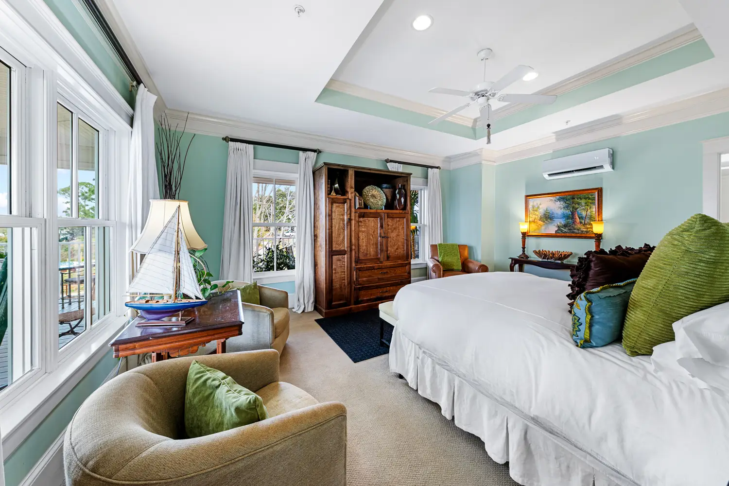 Guest room with a king bed and sitting area in pale blue at Emma's Bayhouse bed and breakfast