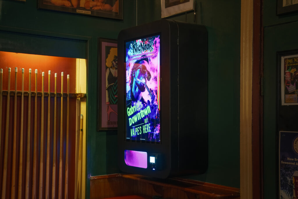 Product Photography 6 NicNook vending machine installed in a dim bar hallway with warm pendant lighting and framed artwork on the walls