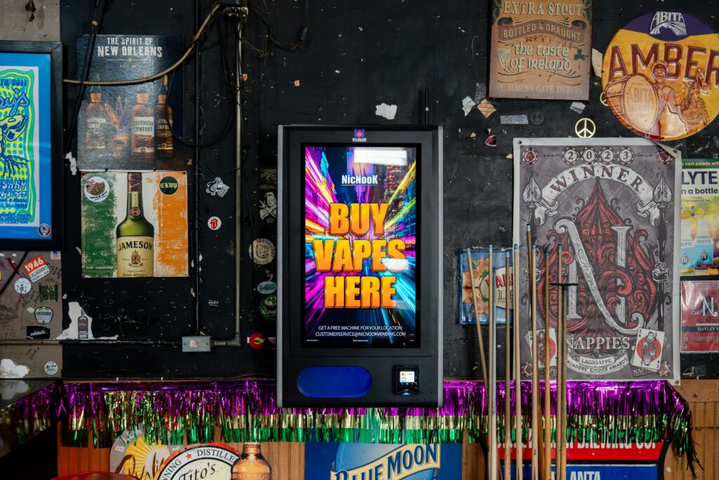 NicNook vending machine installed on a bar wall among beer signs and bottle displays, its lit screen standing out against the clutter